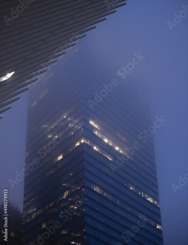 Vertical shot of the lights of a skyscraper in a fog