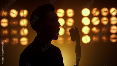 Silhouette singing man vocalist using microphone on show stage nightclub closeup