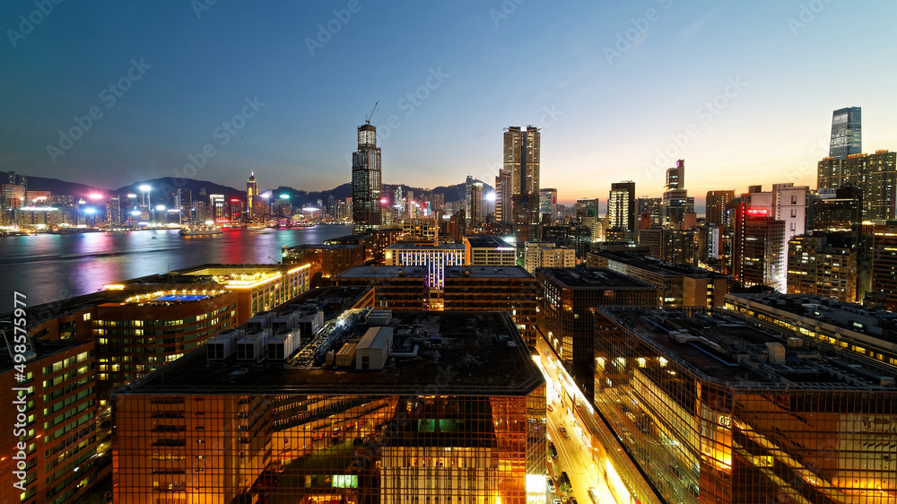 Night scene of Hong Kong, viewed from Tsim Sha Tsui Downtown in Kowloon, with a skyline of skyscrapers by Victoria Harbour and colorful city lights reflected in the water under beautiful twilight sky
