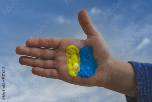 close up view of a kid hand with blue and yellow paint - support Ukraine