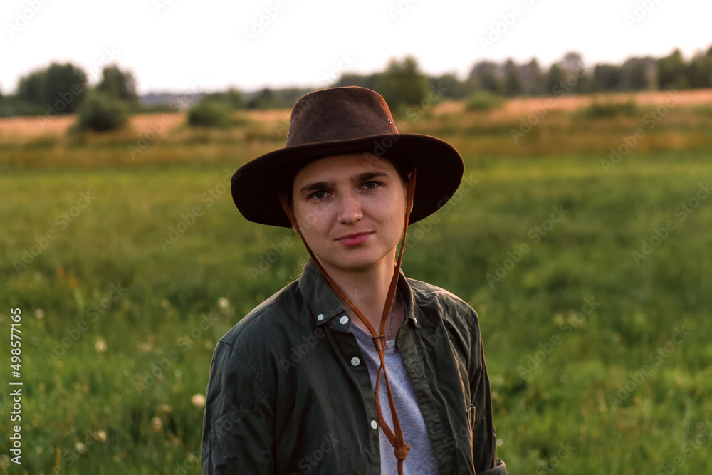 Defocus young woman in cowboy hat. Girl in a cowboy hat in a field. Sunset. Nature background. Closeup portrait caucasian girl. Summertime. Out of focus