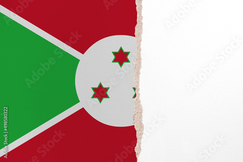 Half- ripped paper background in colors of national flag. Burundi