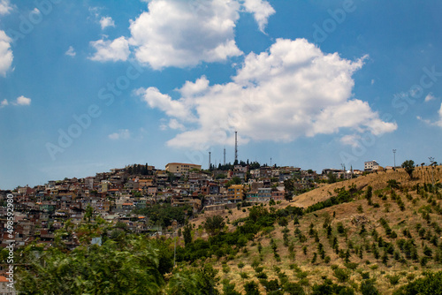 City of Irbid with buildings, houses and trees on hills under a cloudy sky photo