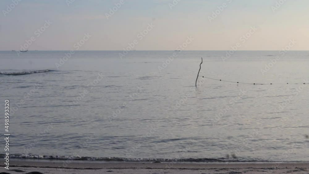 Gelombang laut menerjang di pantai pasir dalam warna oranye yang menakjubkan, matahari terbit pagi yang hangat di lanskap tepi laut dalam pemandangan yang stabil