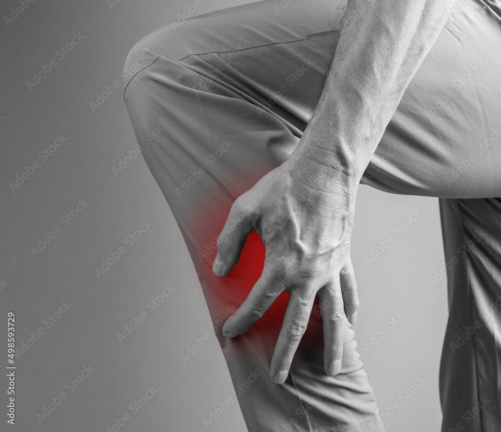 Shin splints. Man holding painful leg with red spot closeup. Overuse