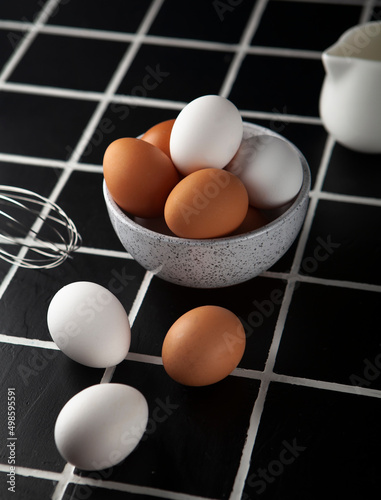 Eggs in the bowl and on the black table 