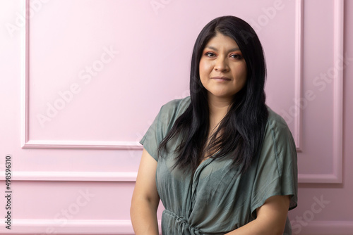 portrait of a mexican empowered woman isolated on pink background