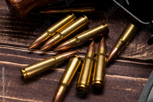 Bullets and Kalashnikov assault rifle on wooden background. Cartridges 7.62 caliber for ak 47 closeup. Selective focus