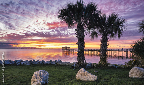 Colorful sunrise over the Rotary Riverfront Park with palms in Titusville, Florida photo