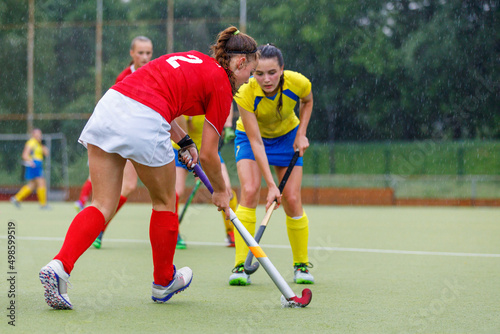 Young female field hockey players struggle for the ball in rainy weather