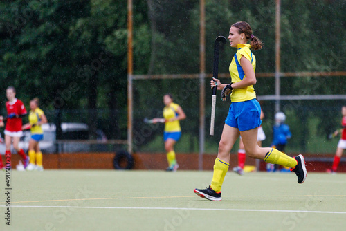 Young teenage girl running on the pitch during the field hockey game in rain © skumer