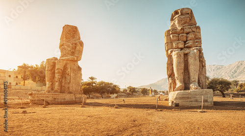 Famous two Colossi of Memnon - massive ruined statues of the Pharaoh Amenhotep III. Travel and tourist landmarks near Luxor, Egypt