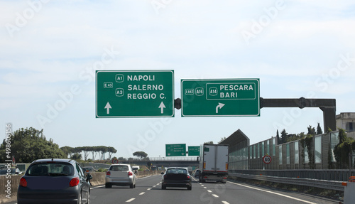 Highway with the signs of the locations of Southern Italy Naples Salerno Reggio Calabria Pescara and Bari with cars running