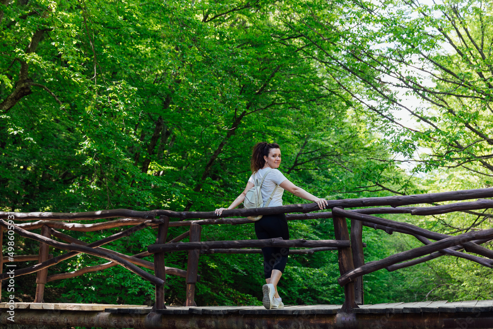 Fototapeta premium a female traveler walks through a green forest on a hike