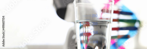 Billede på lærred Glass of water standing near dna molecule mockup and microscope in laboratory cl