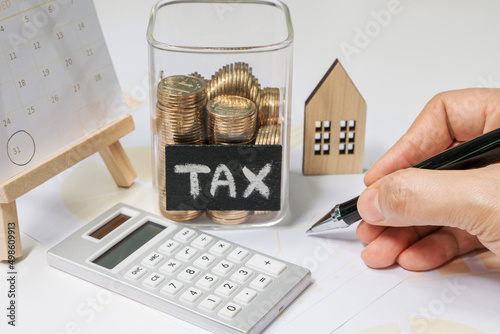 A business woman holding a pen is calculating the tax payable. Calculating annual income tax returns for government sectors concept.