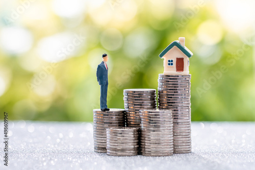 Model home and model businessman putting on coins. Investing in real estate business for profit or a loan for a home purchase concept.