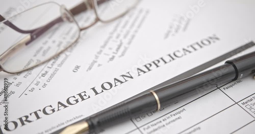 Fountain pen, a glasses on a mortgage loan application form. A mortgage loan is a loan used by a borrower, a property owner, a homeowner, a purchaser of real property to raise funds to buy real estate