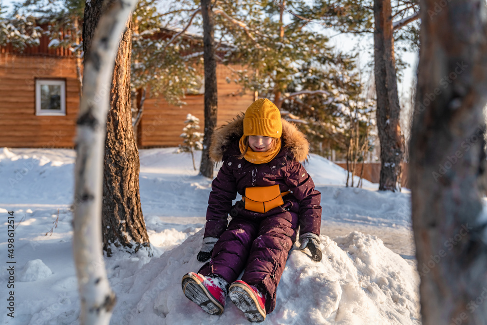 cute girl in winter jumpsuit playing in the snow outdoors.