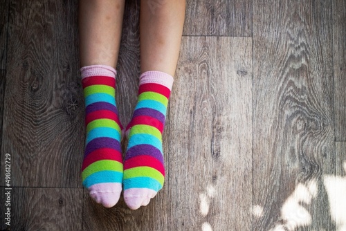 girl child shows two socks with rainbow colors put on her feet as a symbol or concept of lgbt community or protest
