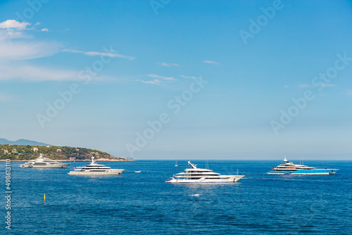 The four huge mega yachts are moored in sea at sunny day, the chrome plated handrail, sun reflection on glossy board of the motor boat © Vladimir Drozdin