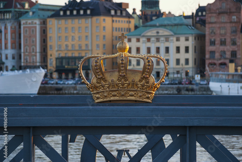 Photography Gold crown on a bridge grille in Stockholm on a sunset light
