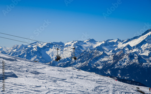 Beautiful winter landscape at Madonna di Campiglio Ski Resort, located at the area of the Brenta Dolomites in Italy, Europe. Chairlift with skiers and snowboarders going up to the peak. © FashionStock