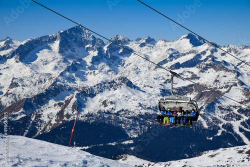 Madonna di Campiglio Ski Resort, located at the area of the Brenta Dolomites in Italy, Europe. Chairlift with skiers and snowboarders going up to the peak.