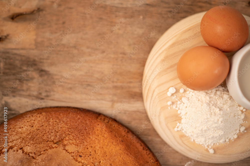Homemade yogurt sponge cake served with fresh eggs, flour and oat milk on a wooden board on a wooden base Homemade yogurt sponge cake served with fresh eggs, flour and oat milk on a wooden board on a wooden base