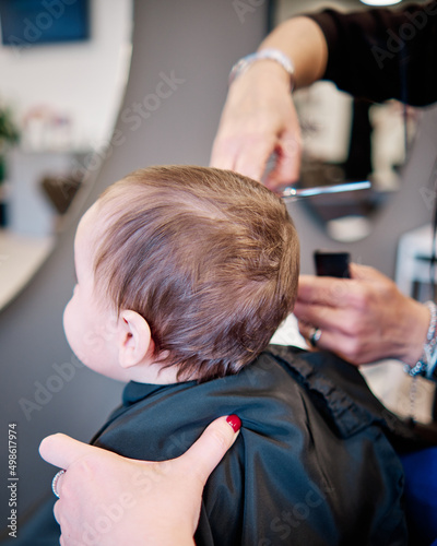 Toddler child getting his first haircut in a beauty salon