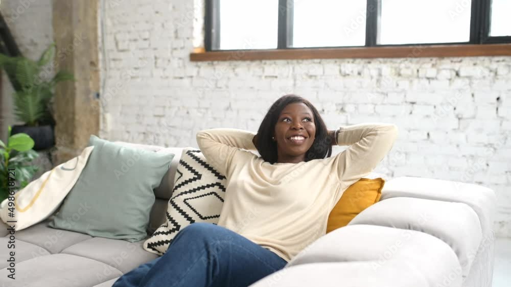 Joyful full of energy woman in casual clothes resting on the sofa, sitting on the couch in modern living room, lady posing and looking at camera, top view Joyful full of energy woman in casual clothes resting on the sofa, sitting on the couch in modern living room, lady posing and looking at camera, top view