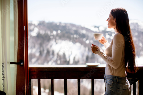 Young woman with cup of hot tea in winter window