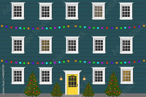 blue apartment building with a door and windows in the evening with a garland for the holiday and christmas tree