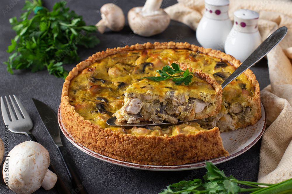 Homemade traditional french quiche pie with turkey, mushrooms and cheese with a cut piece of pie in a plate on a dark textured background Homemade traditional french quiche pie with turkey, mushrooms and cheese with a cut piece of pie in a plate on a dark textured background
