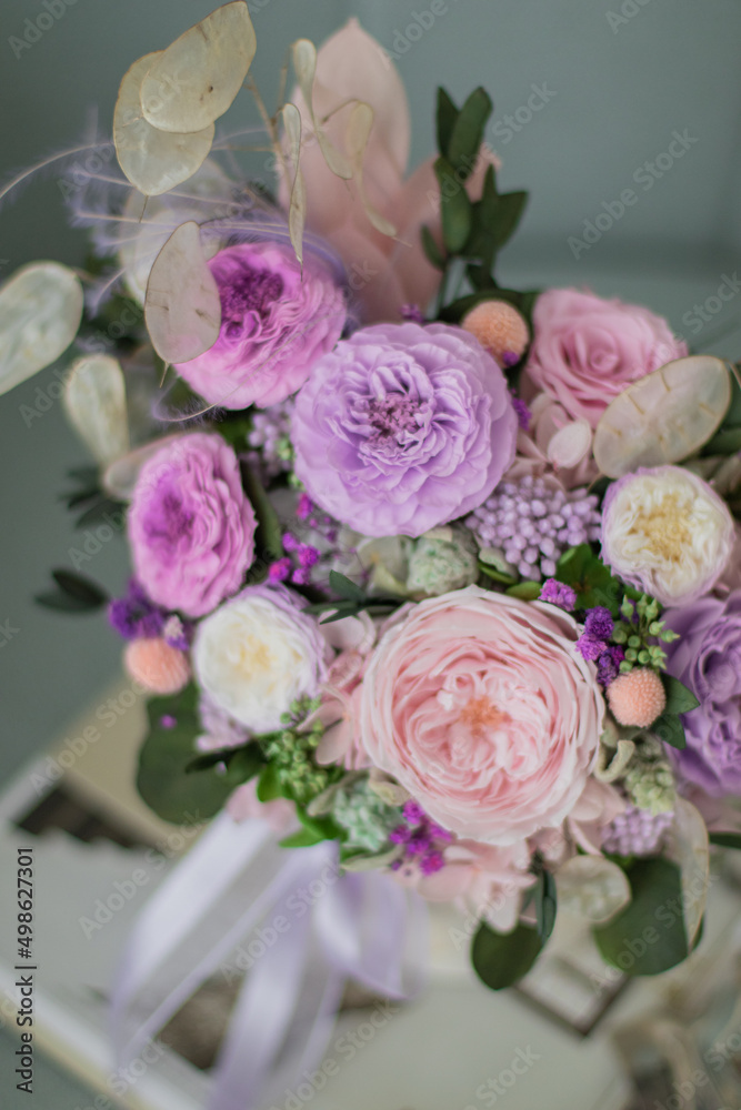 Beautiful spring bouquet in pink and purpl color, in round ceramic vase. Arrangement with Peonies roses. Decorative flowers in a round vase.
