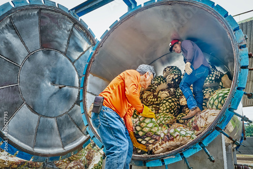 Man piling agave in oven ready to steam it