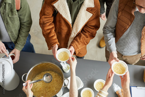 Top down view at group of volunteers giving out simple meals to people in need at soup kitchen photo