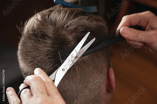 barber cut man's hair, modern haircut with scissors..