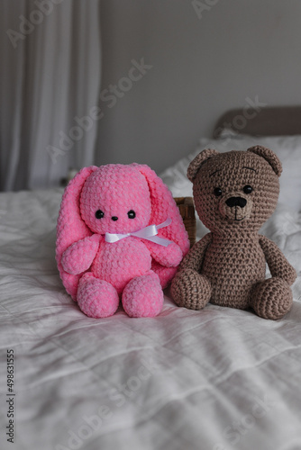 Knitted toy bunny pink and brown bear in a bright room