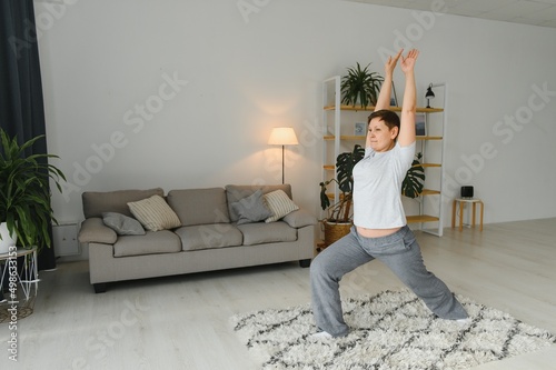 Middle age woman smiling happy doing exercise and stretching at home © Serhii