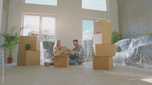 Young happy couple opening cardboard box. Talking with each other and taking the book out of the box photo