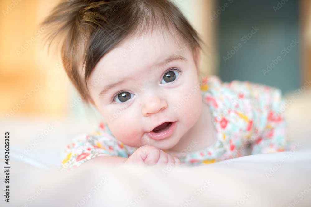 A baby lays on her stomach and looks at the camera A baby lays on her stomach and looks at the camera