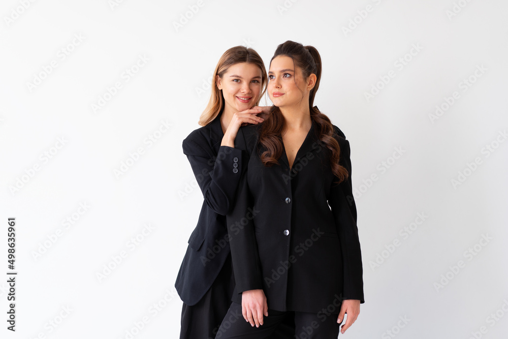 Concept of partnership in business. Two Young businesswoman dressed black formal suit standing studio isolated white background. Concept of partnership in business. Two Young businesswoman dressed black formal suit standing studio isolated white background.