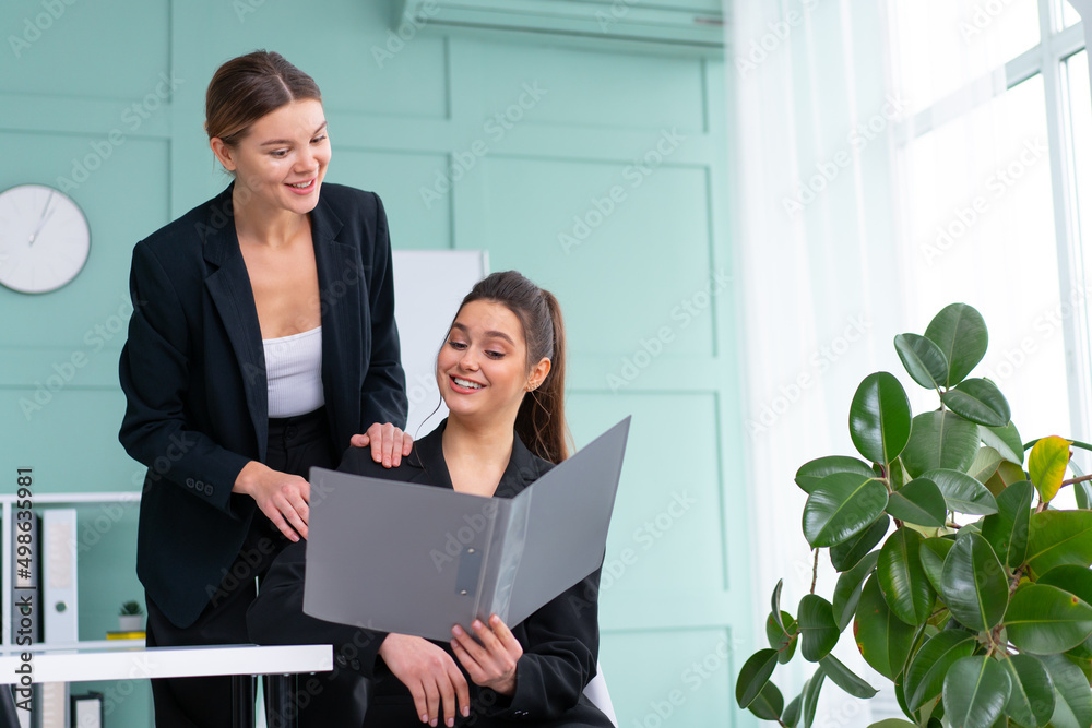 Young women leaders are checking financial statements from paper documents. Two female confident business worker dressed black suit in office checking financial document