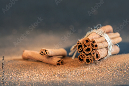 Fragrant cinnamon sticks in a bunch close-up on a dark background with bokeh. Selective focus, blurred background with copy space. natural lighting