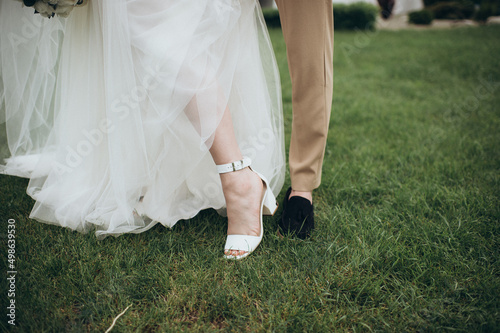 newlyweds stand on the grass, legs close-up