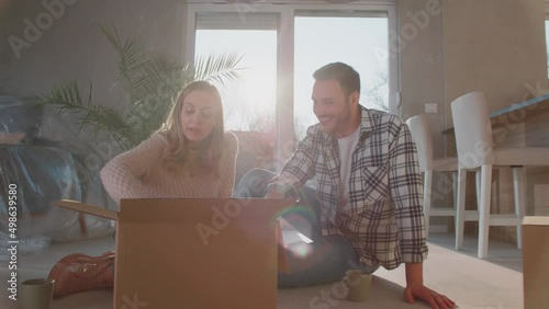 Lovers are sitting on floor in newly bought apartment, elegantly dressed man is holding coffee mug photo