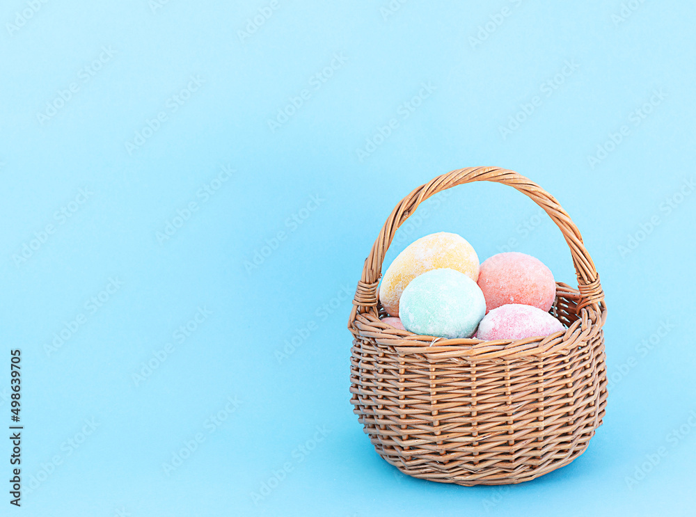 Easter concept. Wicker small basket with colorful Easter eggs on a blue background. copy space.