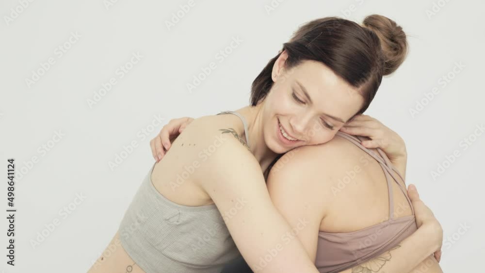 two girls hugging while sitting on a yoga mat. Girls smile and pat each other on the back two girls hugging while sitting on a yoga mat. Girls smile and pat each other on the back
