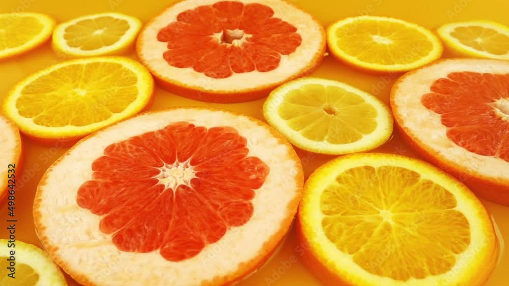 Slices of lemon, orange and grapefruit on an orange background. Water splash. Slow motion. Slices of lemon, orange and grapefruit on an orange background. Water splash. Slow motion.